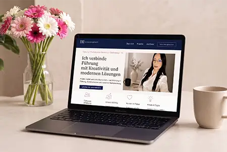 Laptop-Mockup der Website diana-duquenoy.com mit der Startseite „Ich verbinde Führung mit Kreativität und modernen Lösungen", auf einem Schreibtisch mit Blumenstrauß und Kaffeetasse