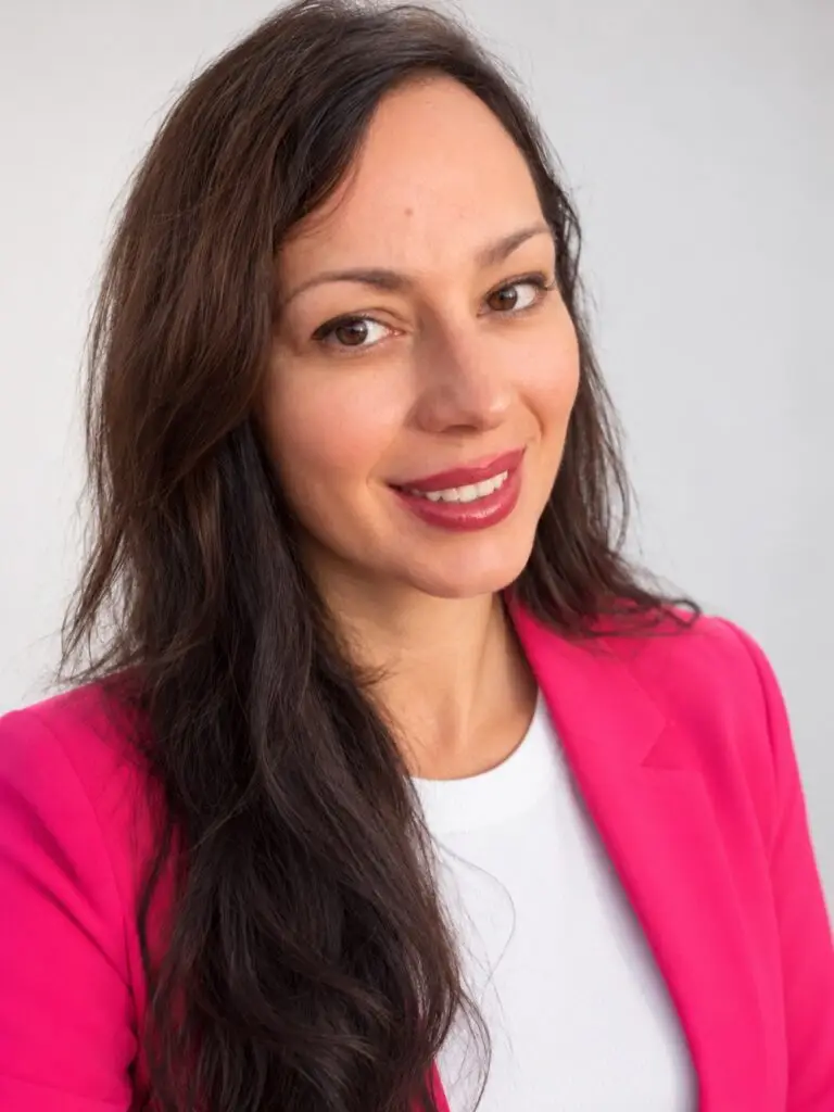 Diana Duquenoy, Marketing-Managerin und Grafik-Designerin, lächelt in die Kamera, trägt einen pinken Blazer über weißem Shirt.